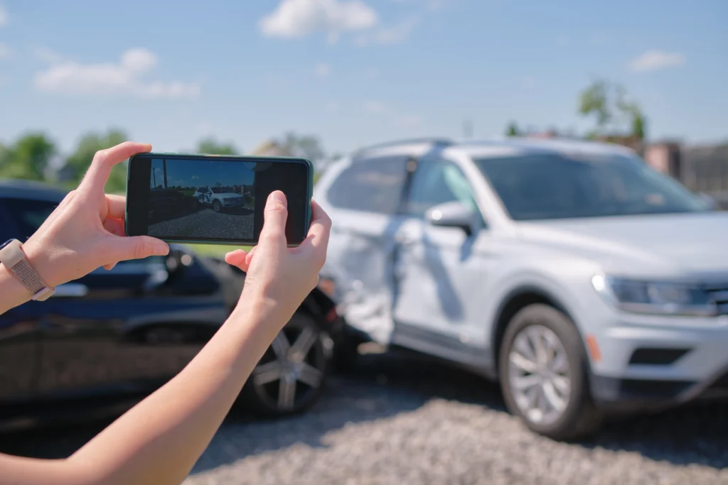 Female taking picture of damaged cars for sale.