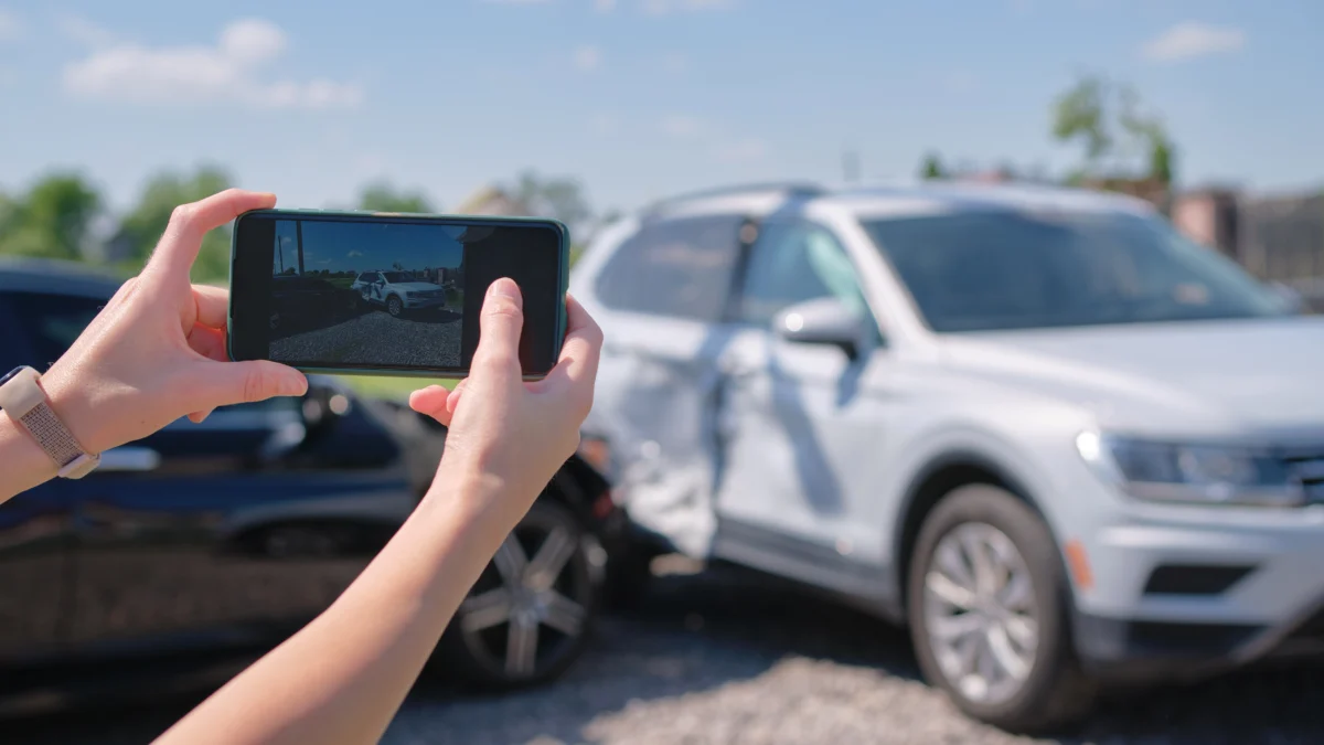 Female taking picture of damaged cars for sale.