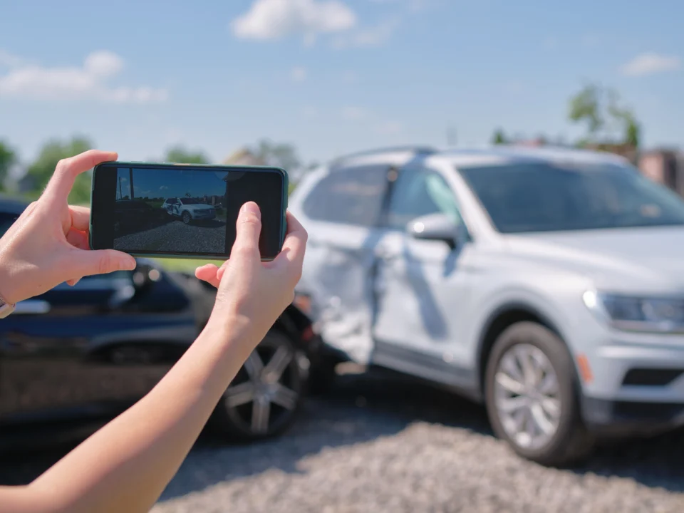 Female taking picture of damaged cars for sale.